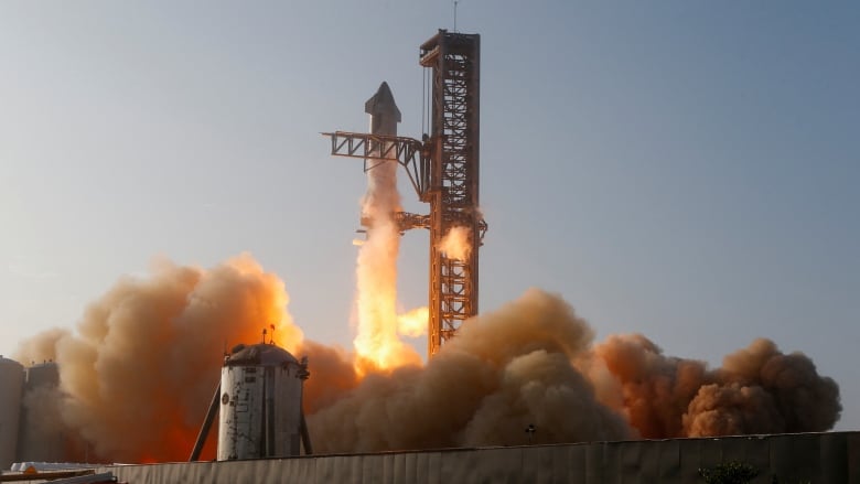 A gleaming silver rocket lifts off with fire and smoke below it.