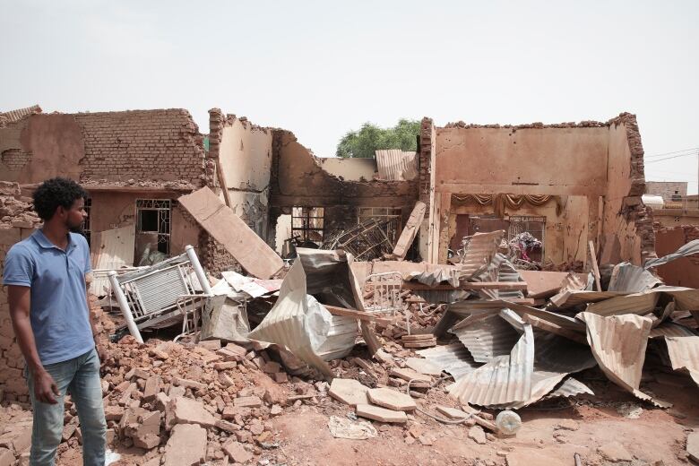 A man looks toward a home damaged by recent fighting in Khartoum, Sudan.