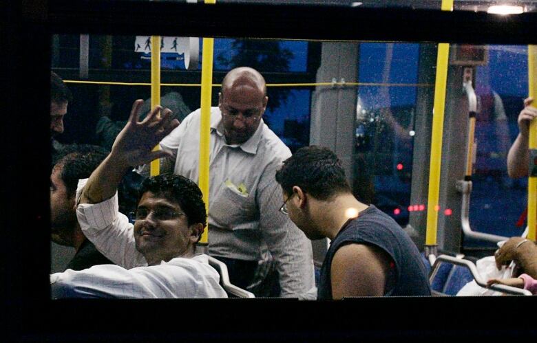 An unidentified man waves from a bus after landing in Ottawa.