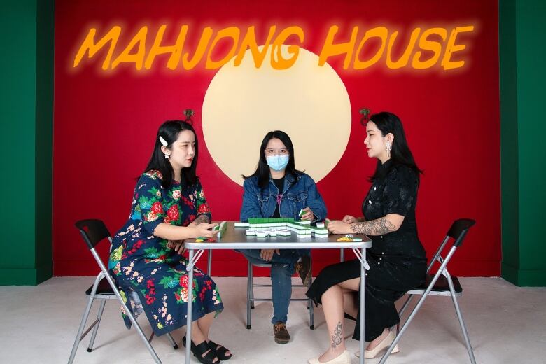 Three women sit around a table playing mahjong