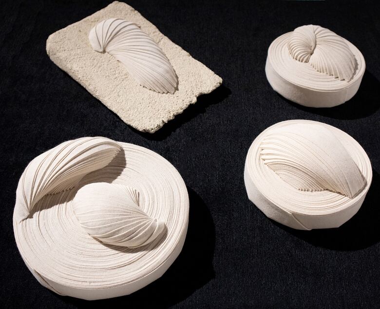 Four sets of white cotton sea shells are displayed on a black background