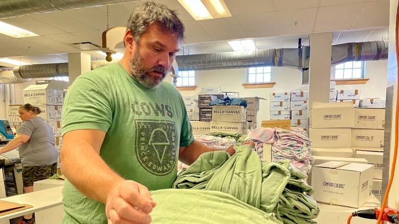 A worker at Cows Creamery organizes company t-shirts in one of the production rooms. 