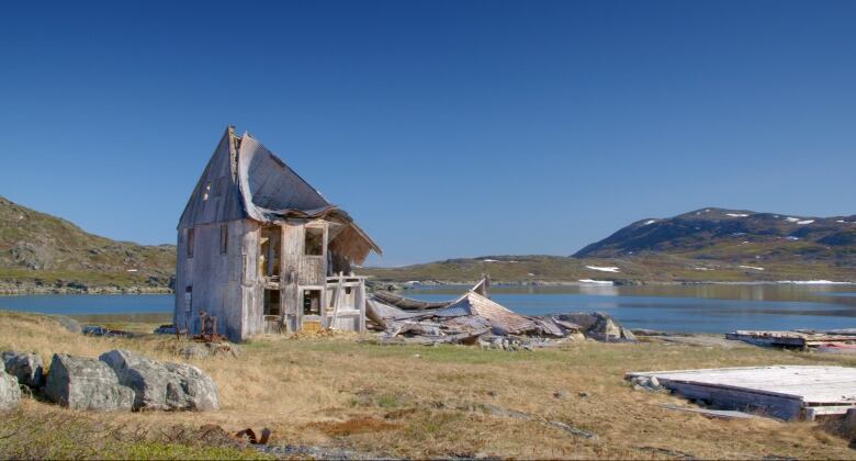 A building is half demolished on the coast with the ocean to the right. 