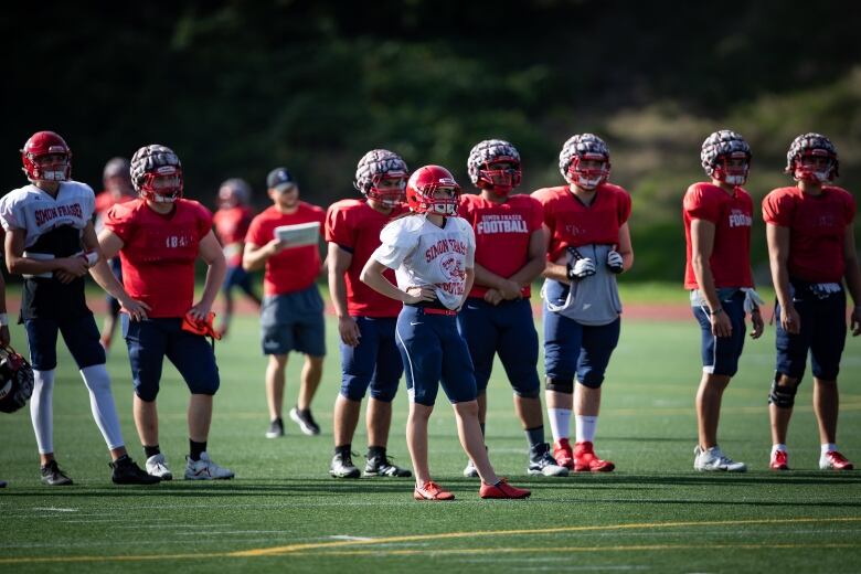 Football players stand on the field in full gear during a practice in Burnaby, B.C.