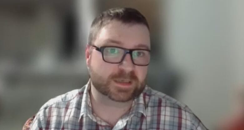 A man with a beard and glasses speaks on a Zoom call.