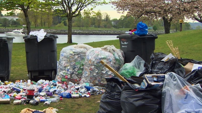 Garbage receptacles overflowing with garbage and beverage containers in a park in Vancouver.