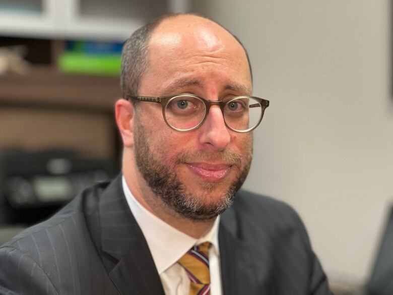 Man with glasses in a suit.