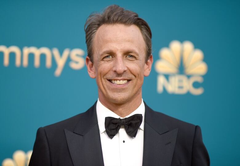 A man in a tuxedo smiles while posing for a photo.