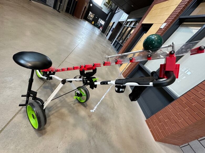 A golf cart with a plastic ramp holding a bocce ball 