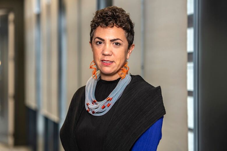 Portrait of a woman with short curly hair, lawyered scarves and brightly coloured jewelry. 