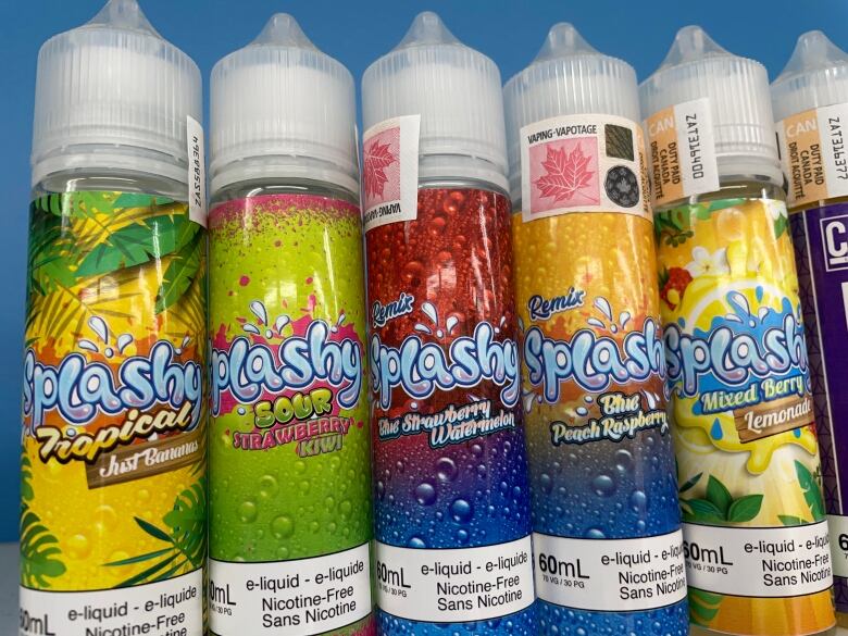 Five plastic bottles with colourful packaging. They all contain liquid for e-cigarettes.