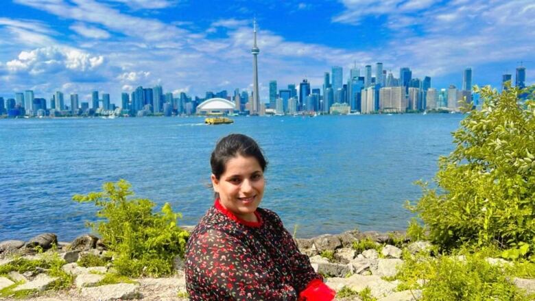 A woman poses with the Toronto skyline behind her