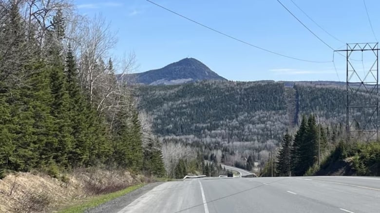 A highway decends into a valley before a mountain that rises in the distance. 