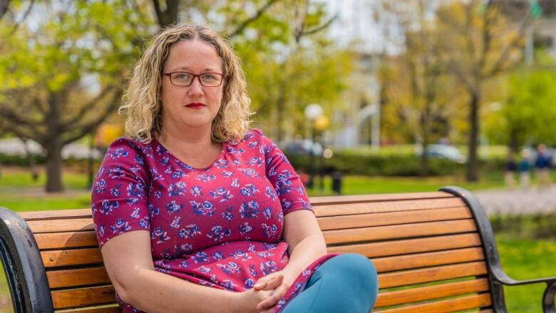 A woman sits on a park bench. 