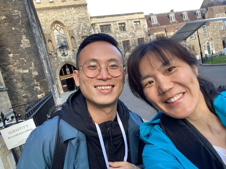 A man and a woman stand outside of a historical church smiling. 