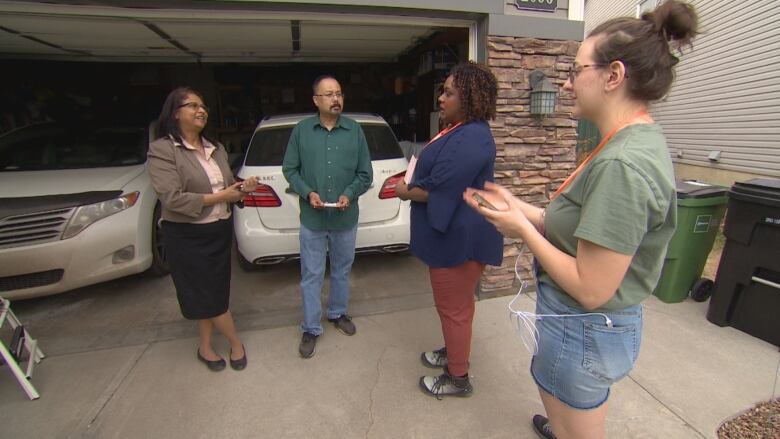 Edmonton-South NDP candidate Rhiannon Hoyle (second from right) speaks to Prajitta and Gautom Bardoloi in front of their home as her volunteer coordinator Liz Dolcemore looks on