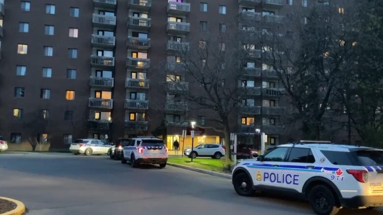 Police vehicles outside a highrise apartment on a spring evening.