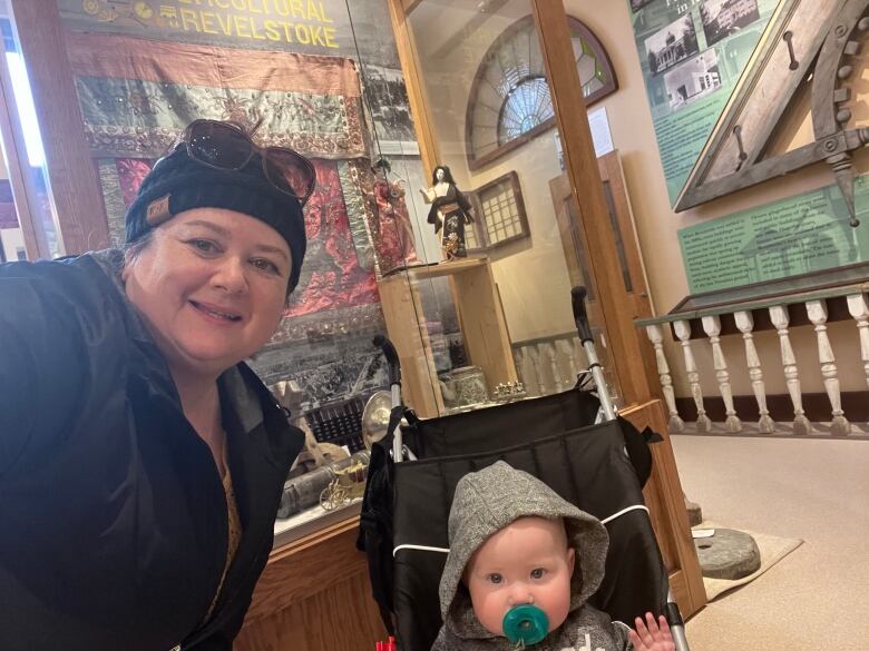 A woman with a baby in a stroller in front of museum exhibits.