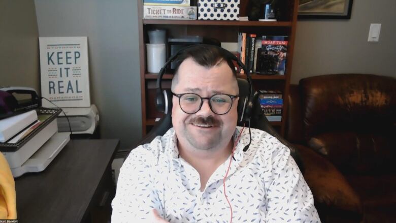 A man with glasses sitting at a desk in an office.