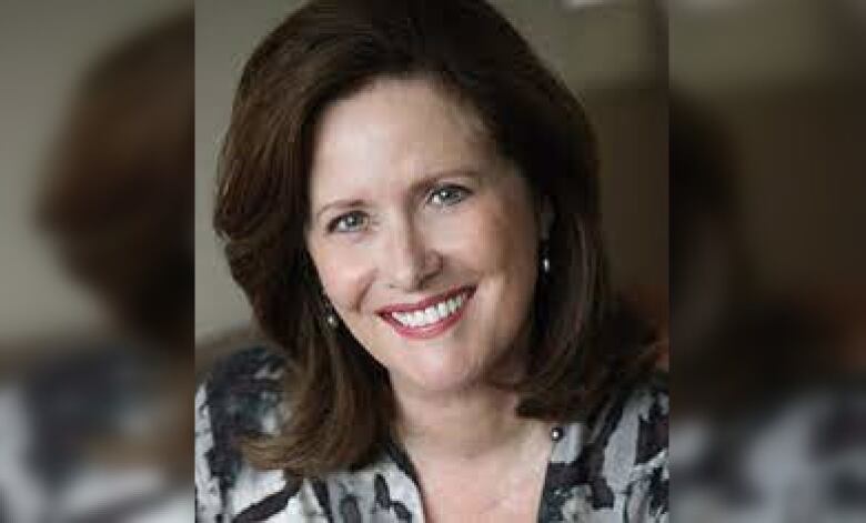 A woman with long brown hair smiles at the camera