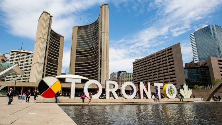 Toronto city hall and a large Toronto sign are pictured.