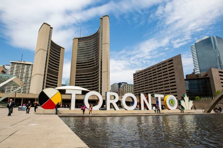 Toronto city hall and a large Toronto sign are pictured.