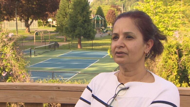 A woman stands on a deck above a pickleball court