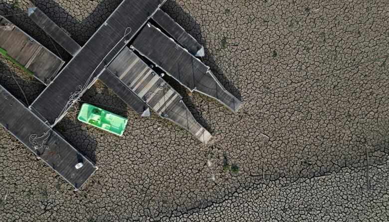 An aerial view showing a pedal boat sitting on cracked ground at a Spanish reservoir.