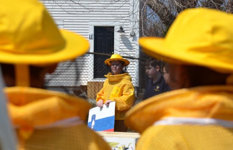 A group of children wearing yellow beekeeping outfits. 