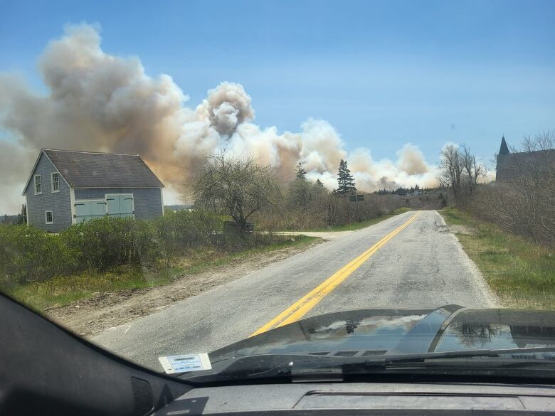 Photo of smoke over a wooded area with a wooden structure in the foreground.