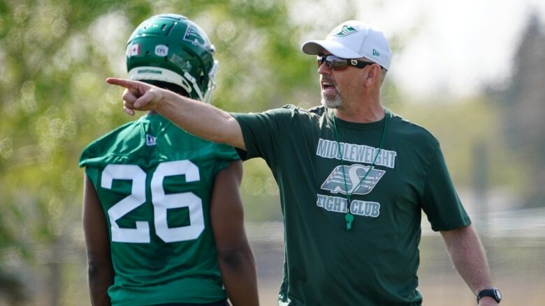 Coach speaking and pointing behind the back of another player.