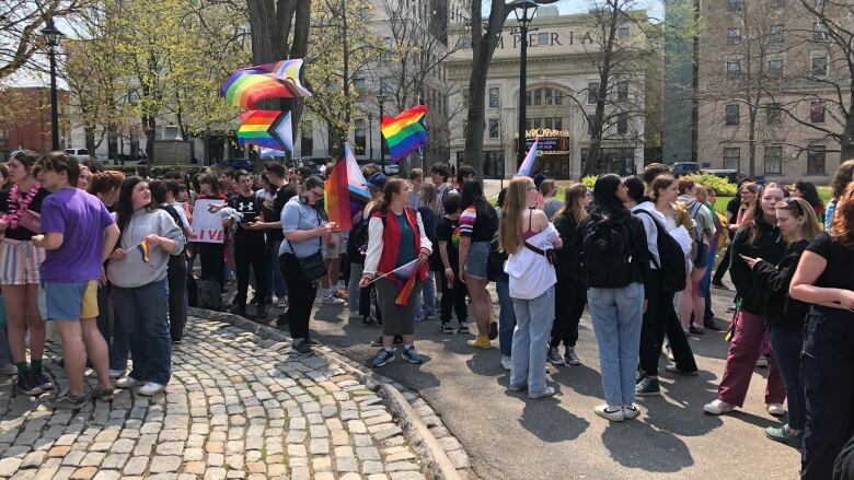 A crowd of people huddled together with some rainbow flags raised in the air.