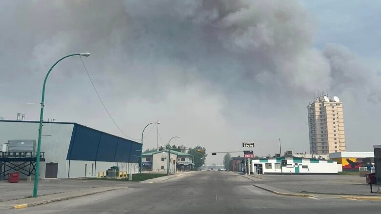 A plume of smoke is seen rising behind some distant city buildings.