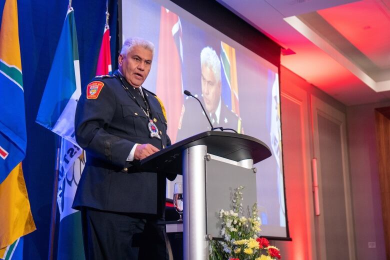 A man wearing a police uniform speaks at a podium.