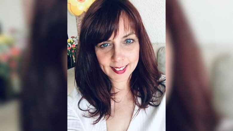 A woman with blue eyes and dark hair smiling at the camera, selfie style.