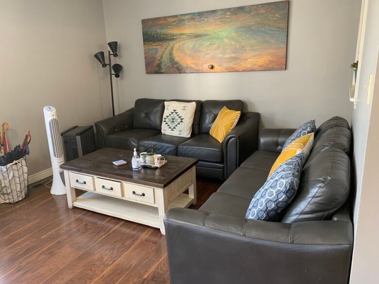 Living room at Blooming House pictured, two large couches and coffee table as well as a decorative painting on one wall. 