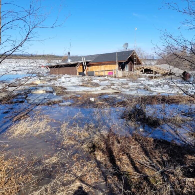 A cabin flooded with water and surrounded by chunks of ice.