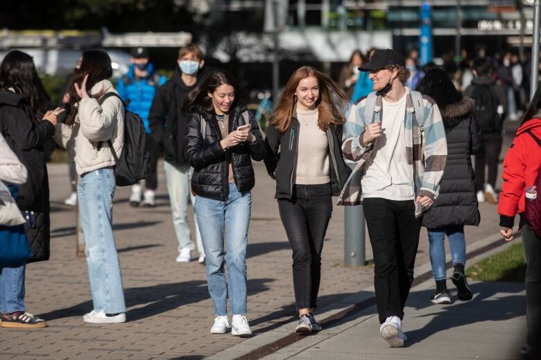 A number of university students walk outdoors in a university.