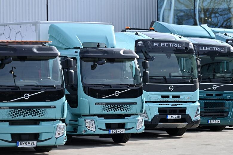 A handful of electric semi-trucks parked next to each other.