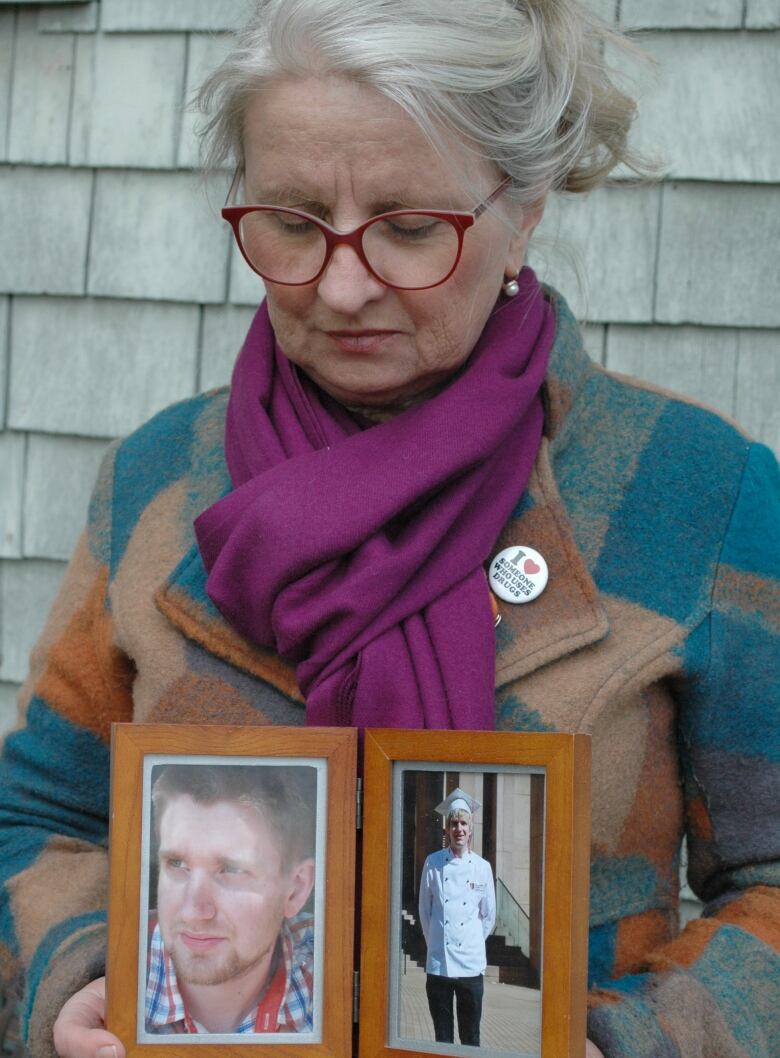 A woman holds a photo of a young man.