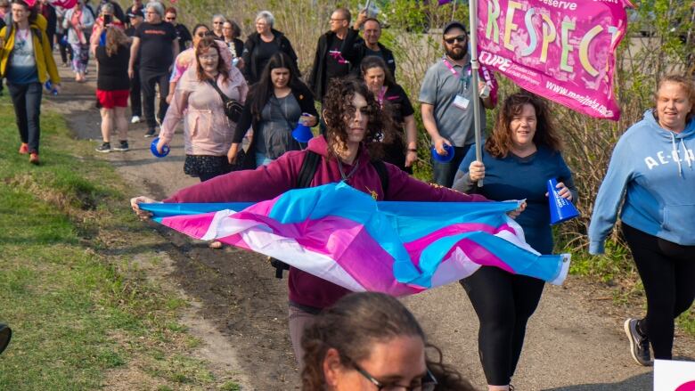 A woman carries a trans flag during a rally.