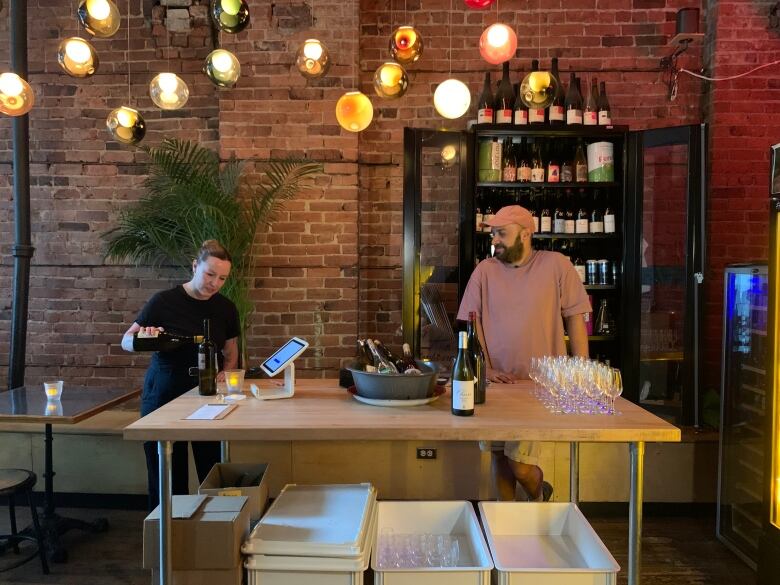 A man and a woman stand at a wine bar. 