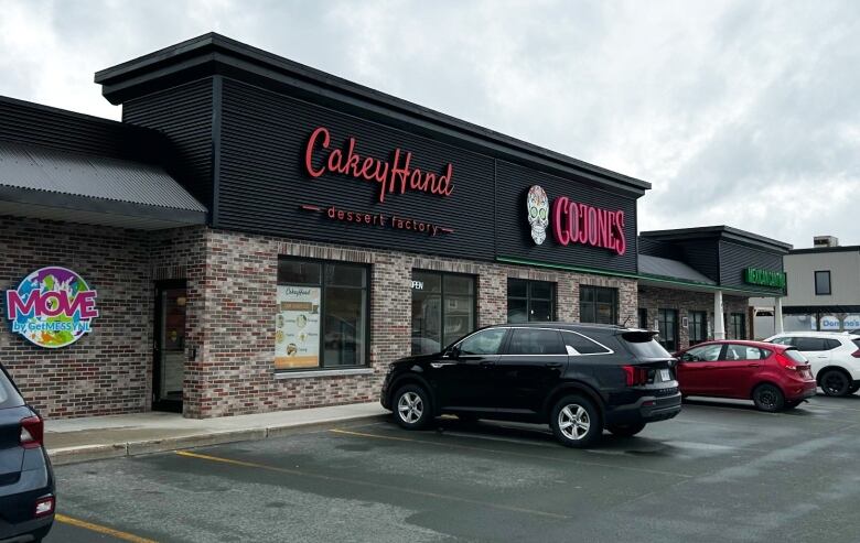 A photo of a building with two signs that read CakeyHand and Cojones. 