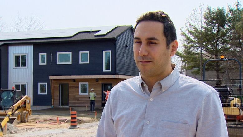 A man stands in front of a row of townhouses being built