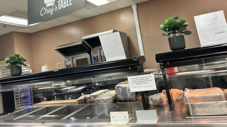 A photo of the Chef's Table cafeteria at the Foothills Hospital shows empty metal food trays behind a glass partition