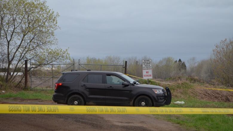 An unmarked police vehicle parked on a dirt road.