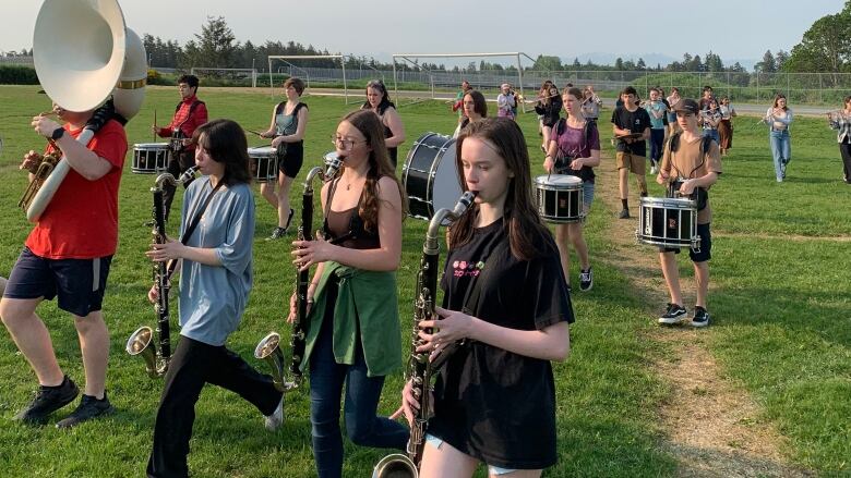 Students in a marching band walk on a school field. 