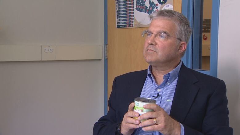 A man is seen holding a can of corn.