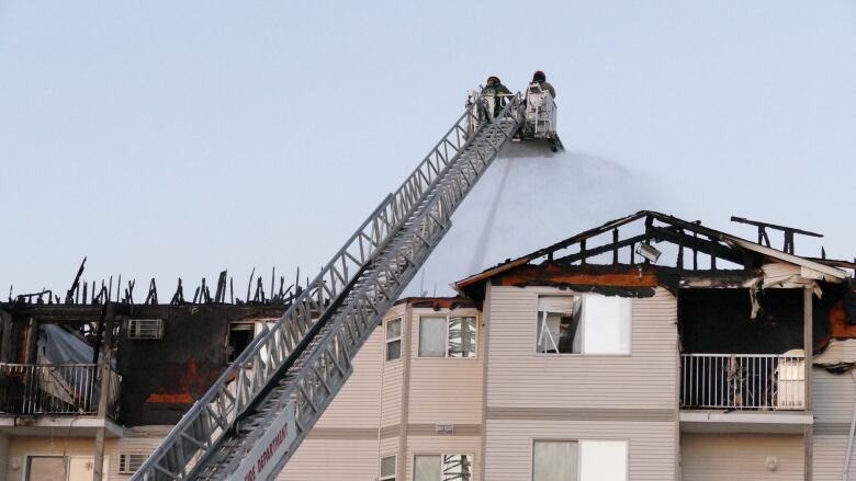 Firefighters on an aerial ladder are shown spraying water on an apartment fire from above.