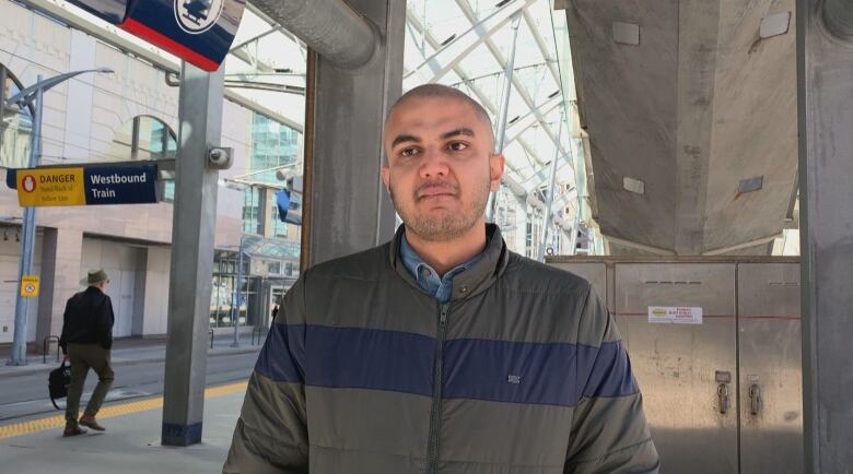 A man stands at a CTrain station.